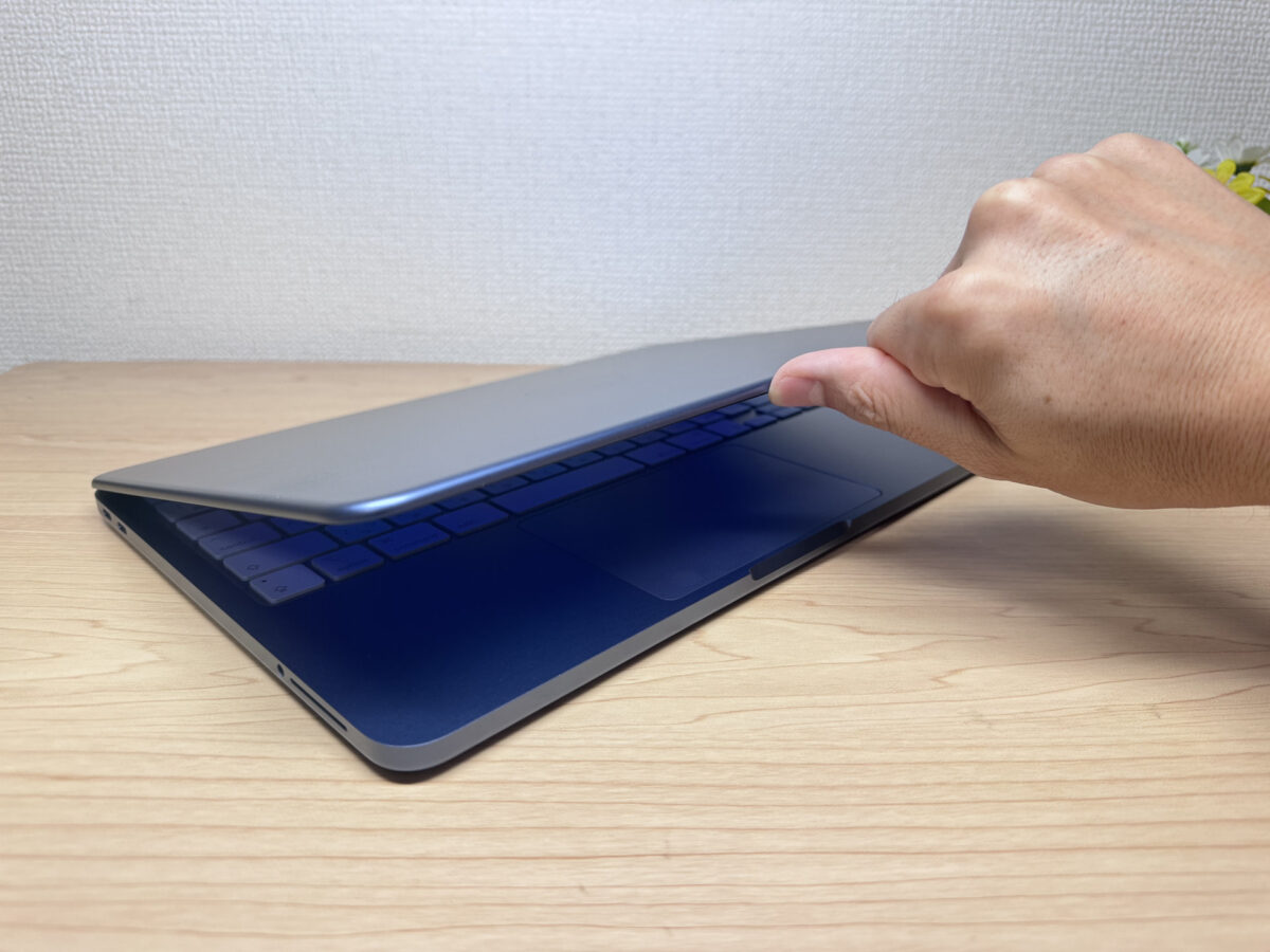MacBook Neo カバーを片手で開ける様子